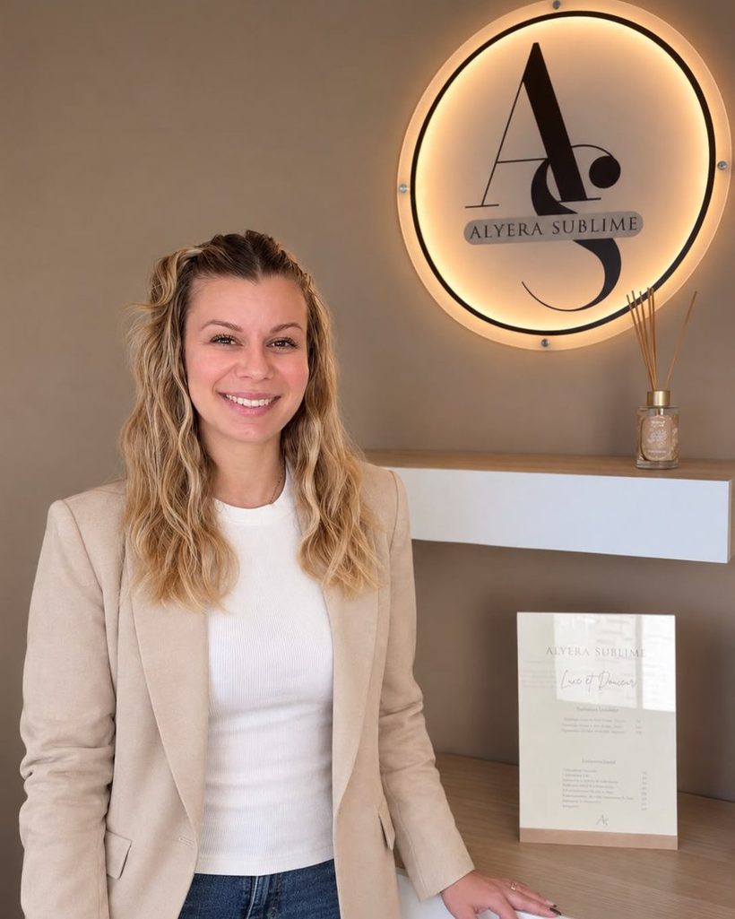 Andrea Schneider, prothésiste ongulaire, dans son institut devant l’enseigne Alyera Sublime